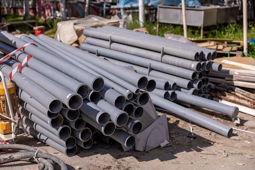 A collection of gray PVC pipes neatly stacked at an outdoor construction site.